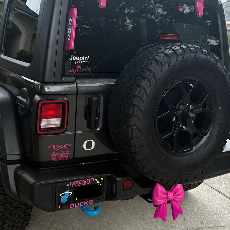Hot pink bow tow hitch cover on black jeep 