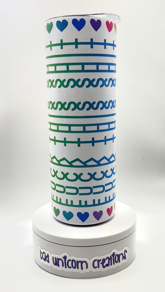 Tumbler with geometric pattern and hearts on a white background and rainbow lettering.
